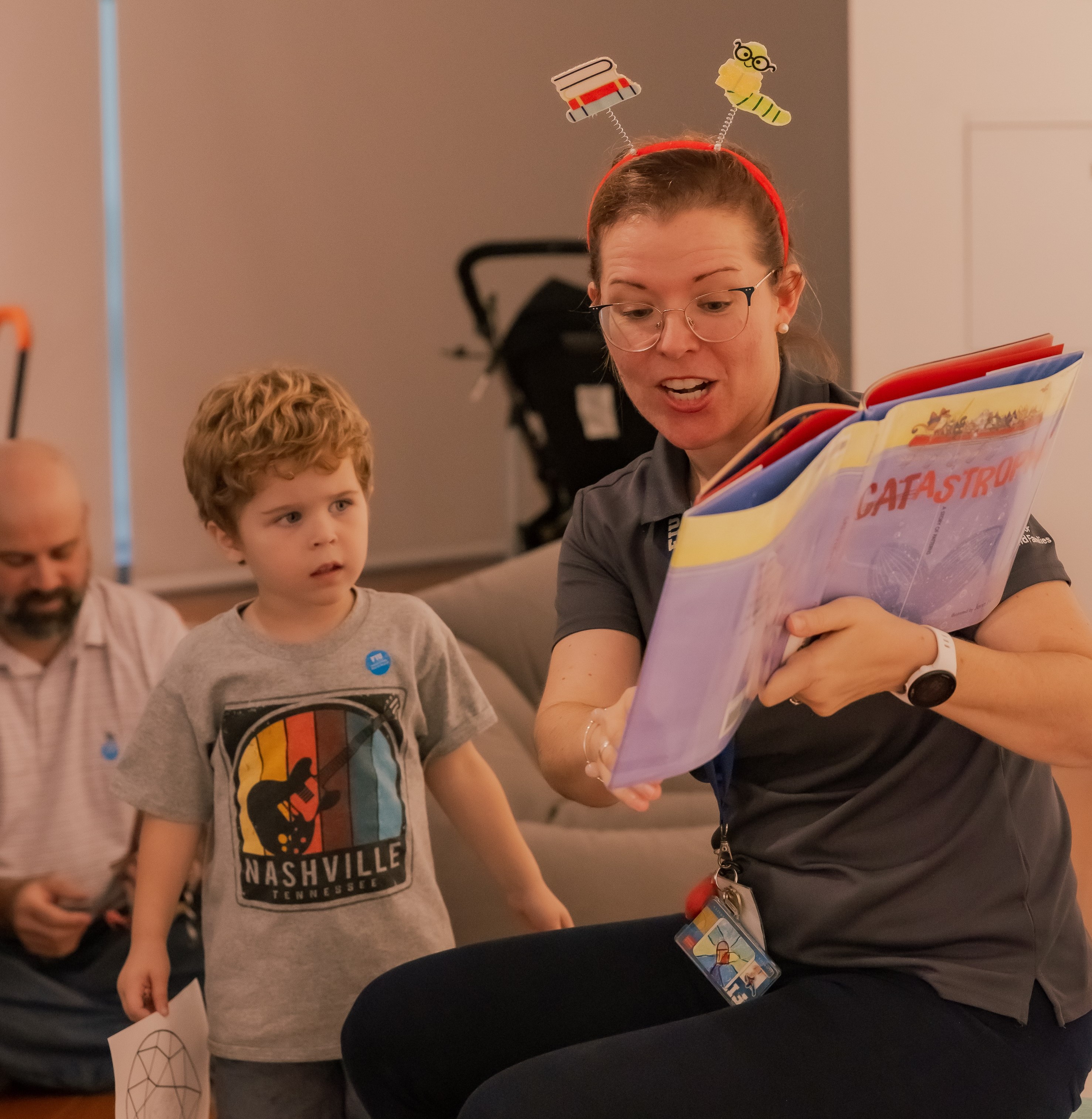 Woman with glasses reading to a young child.