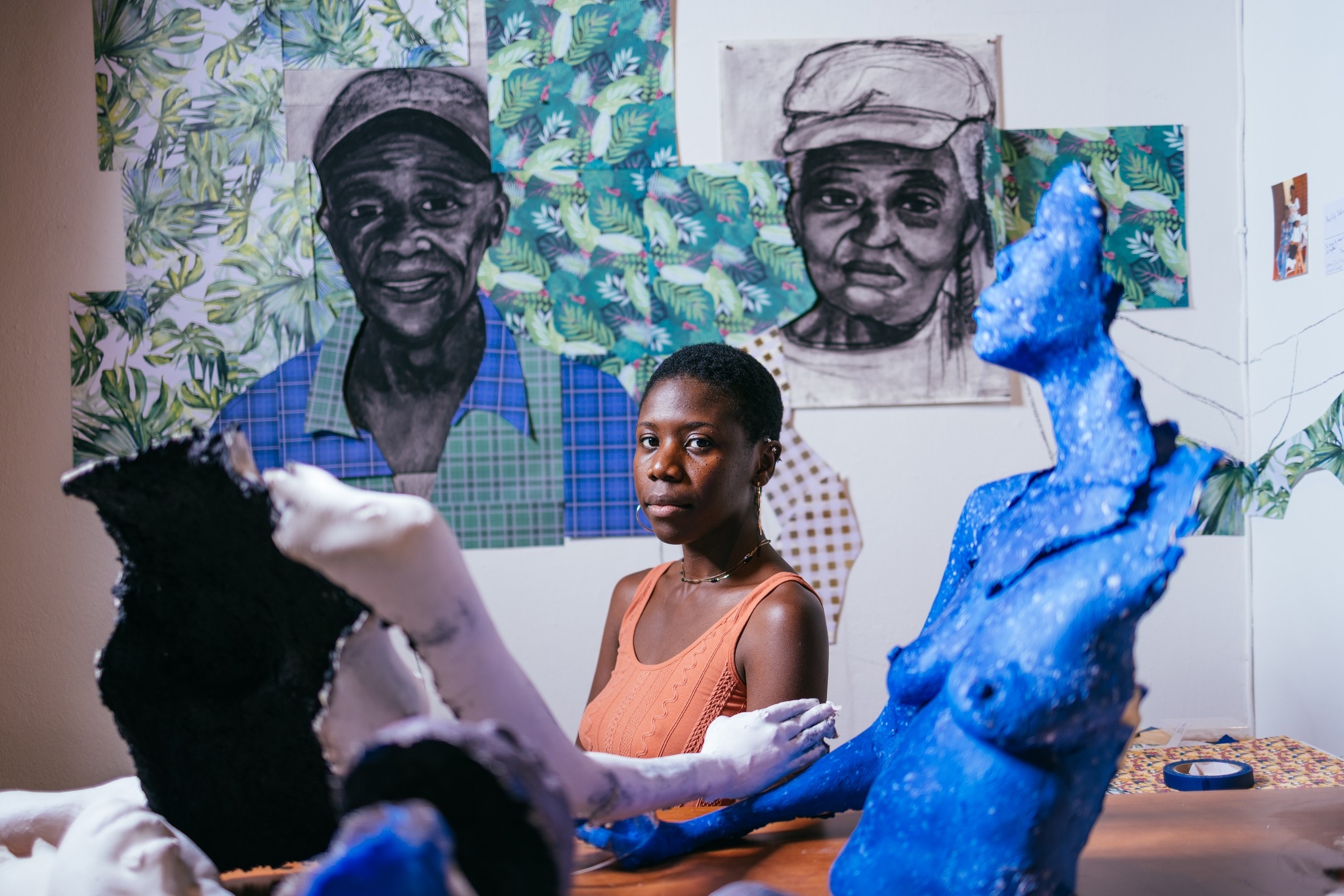 Artist Shawna Moulton sitting with her work on a wall behind her.