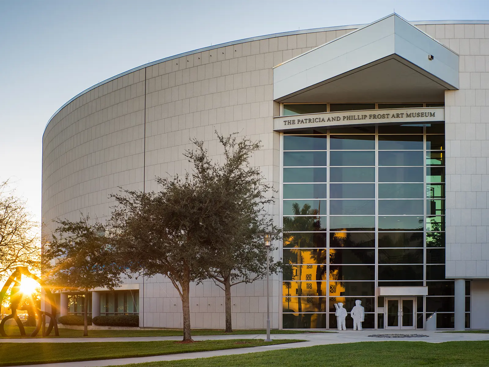 Exterior view of The Patricia and Phillip Frost Art Museum with a curved facade and large glass windows.