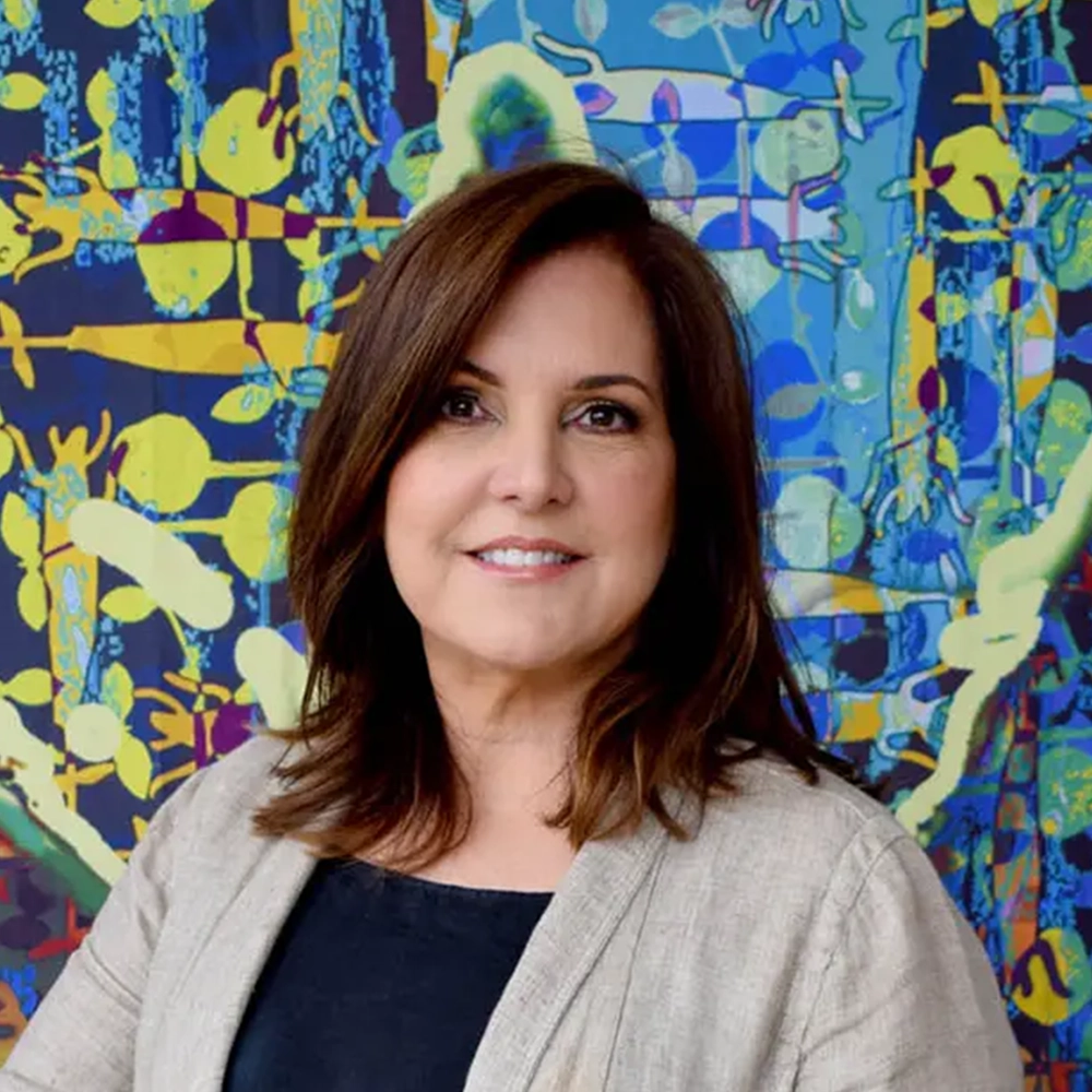 Woman with brown hair posing for a photo in front of art.