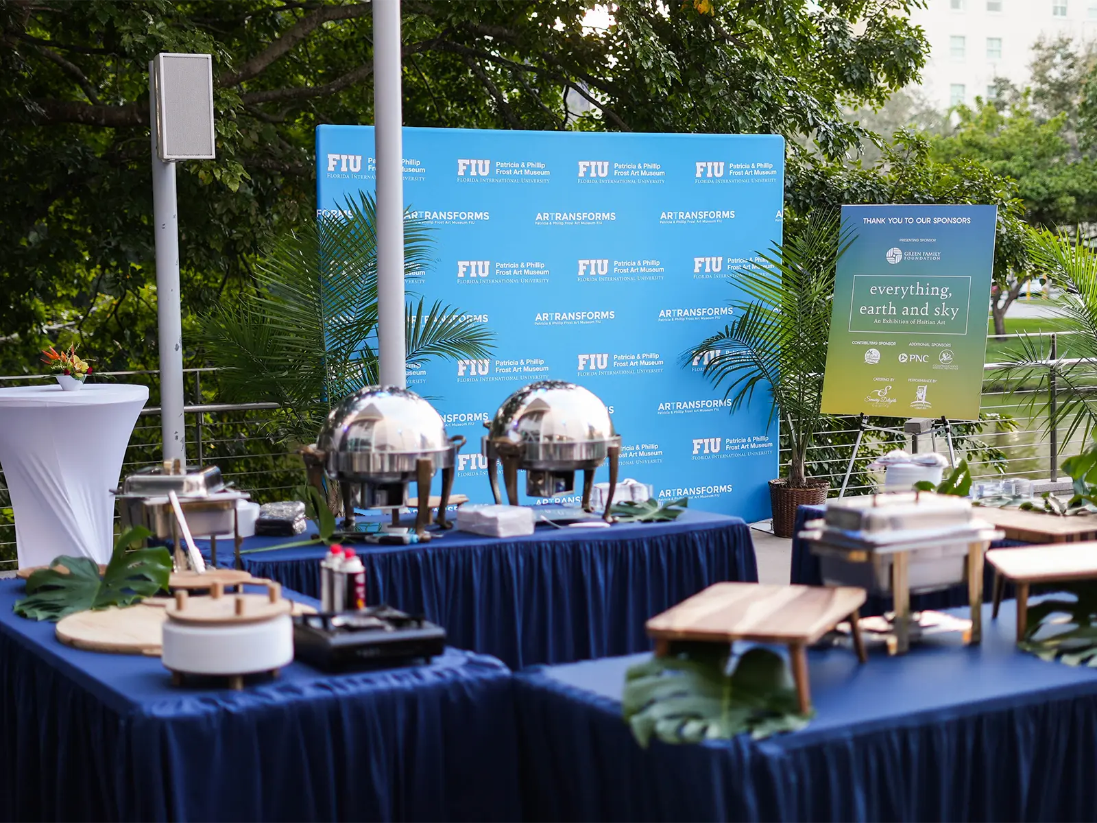 A decorated outdoor terrace with tables, buffet servers, and a step-and-repeat from FIU.