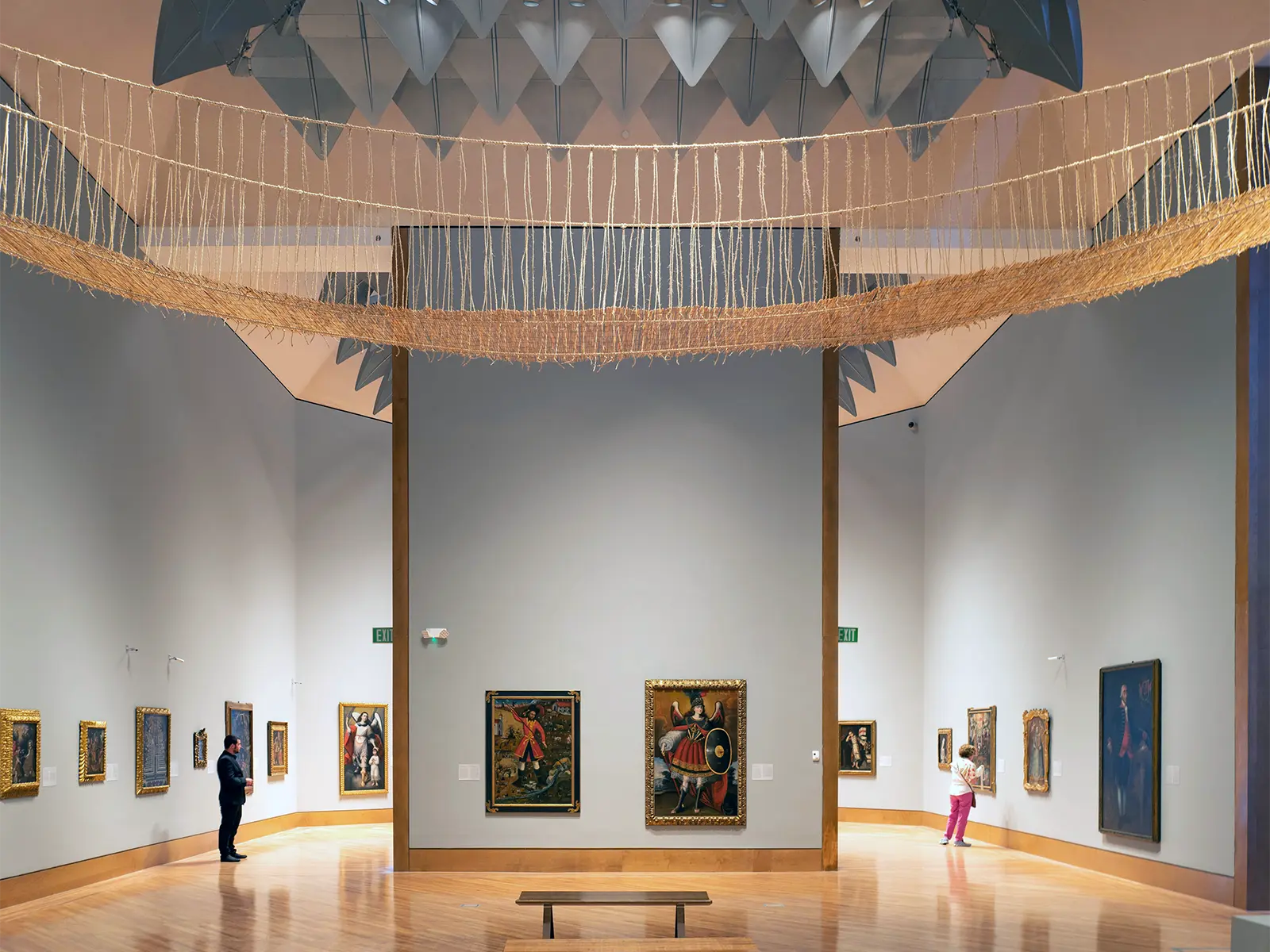 Interior view of an art gallery with high ceilings, geometric skylight, and a suspended sculpture.