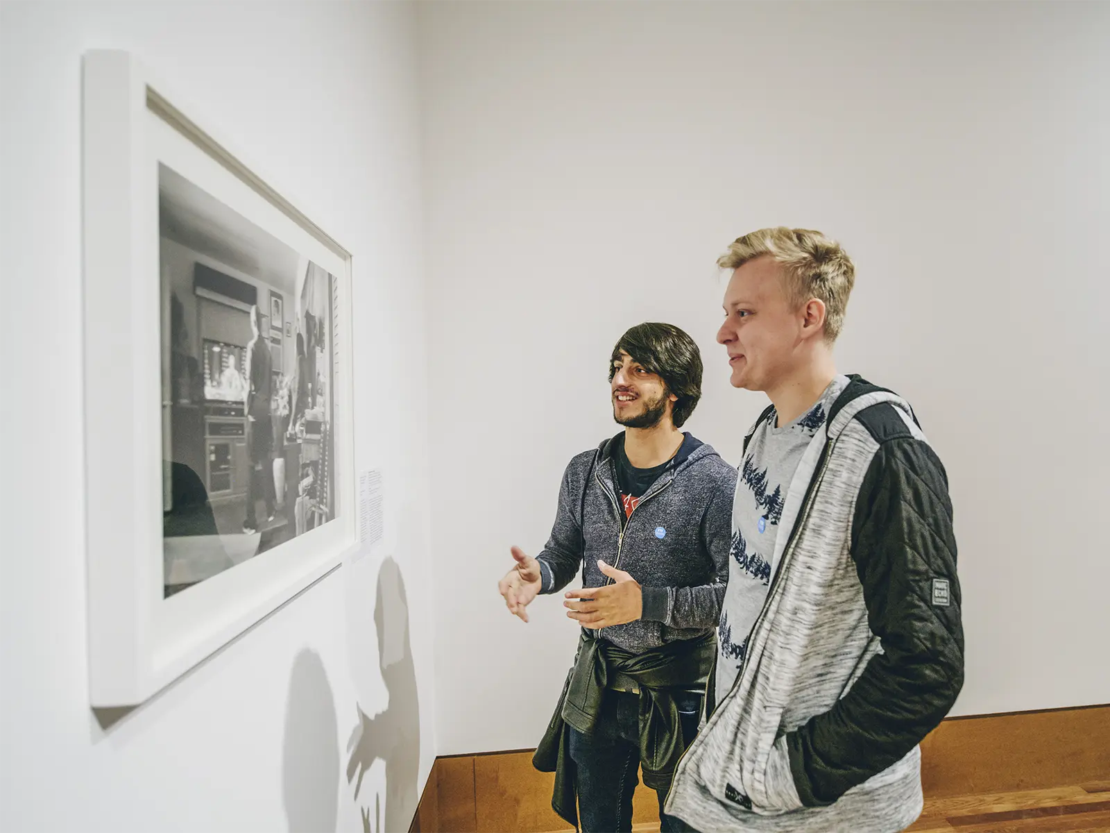 Two students discuss artwork on a wall in a museum gallery