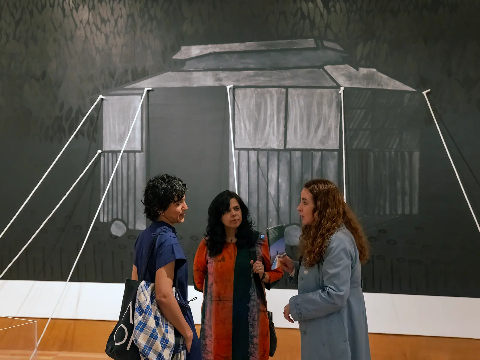 Visitors engaging with a monochromatic art installation at Frost Art Museum, depicting a life-sized tent facade painted onto canvas