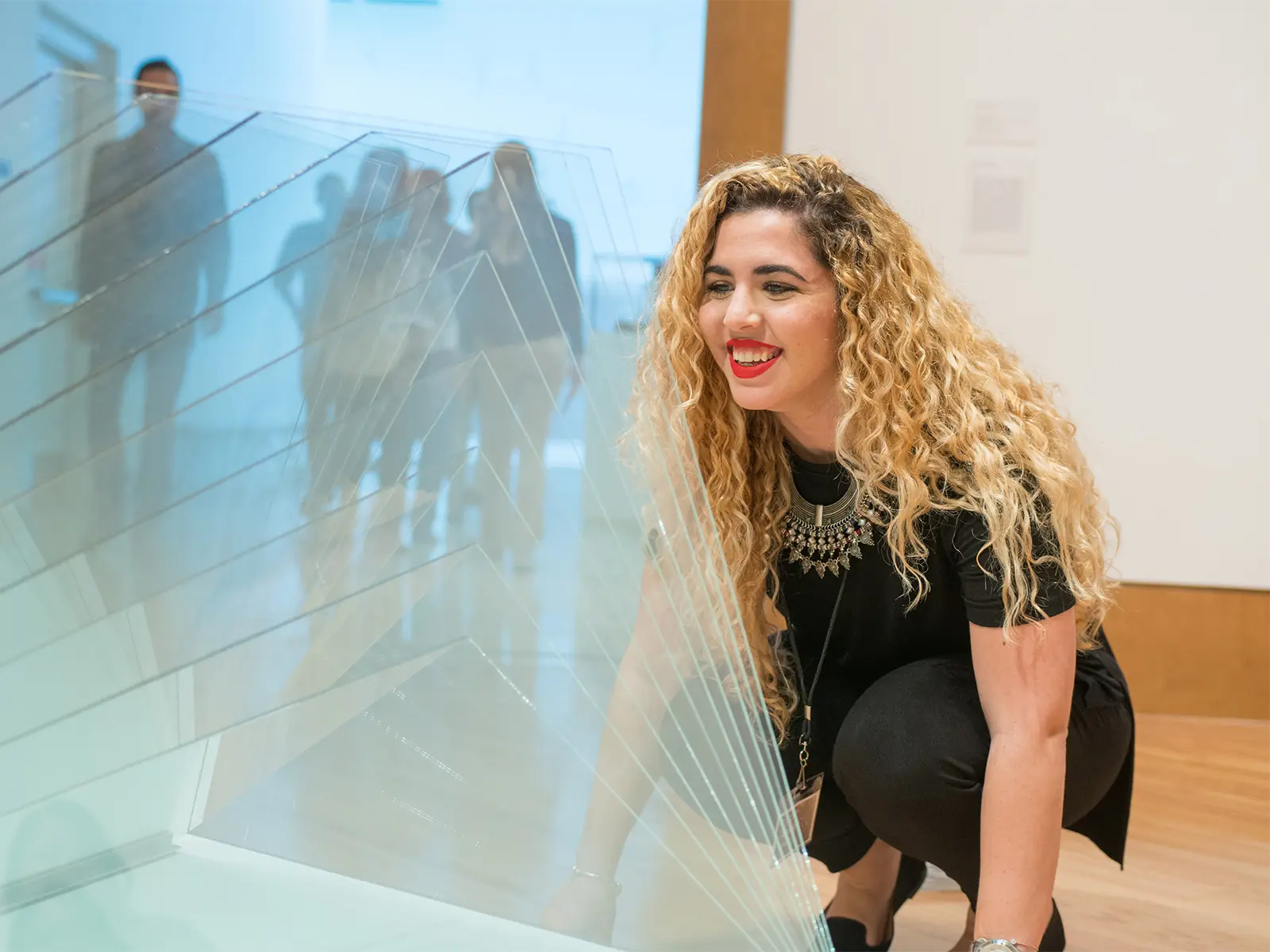 Gallery guide with curly hair admiring a contemporary glass art installation at the Frost Art Museum